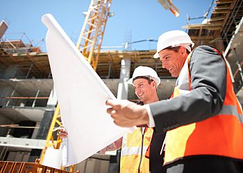 Two Construction Workers Holding Blueprint at Construction Site