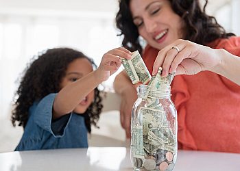 mom and daughter putting money in jar