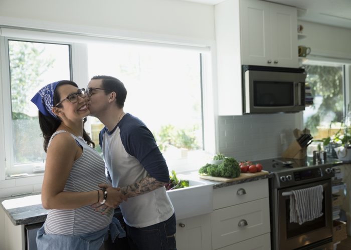 Pregnant Couple Kissing in Kitchen